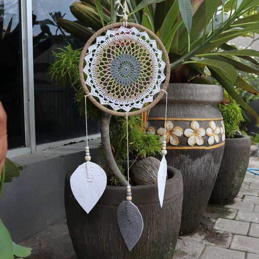 A large brown dream catcher displayed in a garden